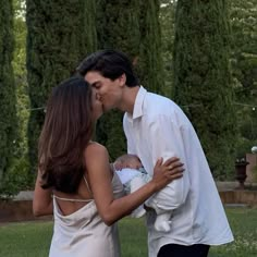 a man and woman kissing while holding a baby