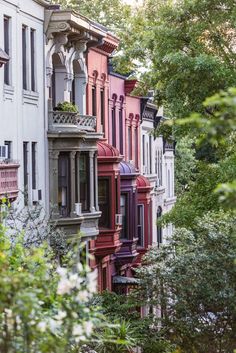 a row of multi - colored houses with trees in the foreground