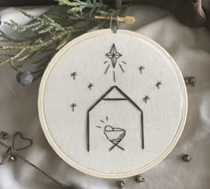 a cross stitch christmas ornament with a nativity scene in the center and stars above it