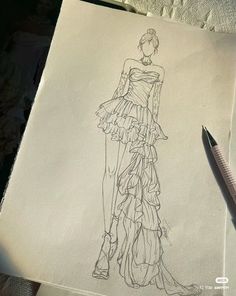 a drawing of a woman's dress on paper with a pen next to it