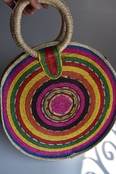 a person holding a multicolored basket in their hand