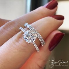 a woman's hand holding an engagement ring with two diamonds on top of it