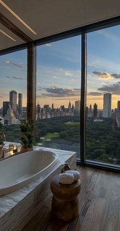 a bath tub sitting next to a large window with a view of the city below