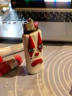 a white and red lighter sitting on top of a table next to a laptop