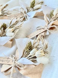 dried flowers are tied to twine on a white tablecloth with brown paper tags