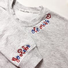 a pair of grey sweatshirts with red, white and blue embroidered on the chest