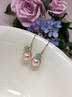 These one of a kind flowering beauties feature soft, blush pink Swarovski Crystal pearls that are meticulously wrapped in 14kt yellow gold filled wire. The braided detailing looks amazing with these pearls. Accented with gold-dusted, aqua Czech glass flowers and gracefully suspended from handcrafted French ear wires. These are perfect for Spring, Summer and for bridesmaids gifts! - All components are 14kt yellow gold filled. - Swarovski Crystal pearls, Czech Glass flower beads. - Pearl dangles a Elegant Pink Gold Flower Earrings, Elegant Pink Petal-shaped Flower Earrings, Handmade Feminine Drop Flower Earrings, Rose Gold Flower Drop Earrings With Pearl, Rose Gold Pearl Drop Flower Earrings, Feminine Rose Gold Earrings For Spring, Rose Gold Flower Earrings With Pearl Drop, Pink Feminine Dangle Flower Earrings, Rose Gold Flower-shaped Earrings With Pearl Drop