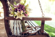 a bouquet of flowers sitting on top of a wooden bench next to a pair of sandals