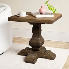 a small table with a book and cup on it in front of a white chair