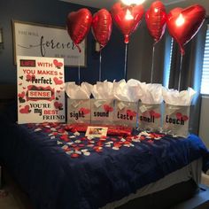 a table topped with lots of red heart shaped balloons and paper bags filled with hearts