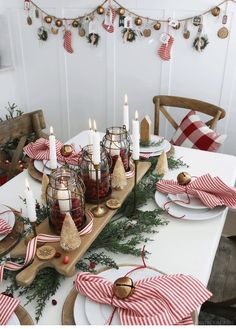 a dining room table decorated for christmas with red and white striped napkins on it