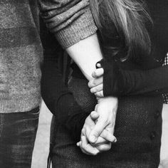 black and white photograph of two people holding each other's hands with their arms