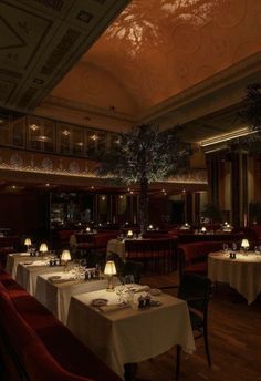 a dining room with tables and chairs covered in white tablecloths, lit by lamps