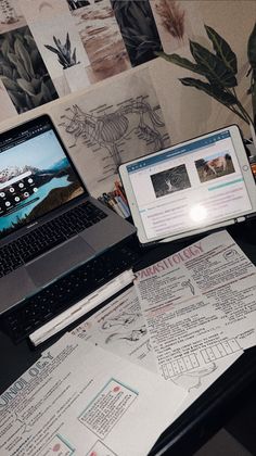 an open laptop computer sitting on top of a desk next to a phone and papers