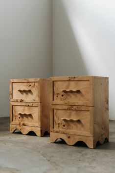 two wooden drawers sitting next to each other on the floor in front of a white wall