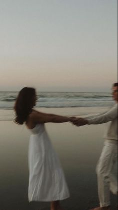 two people holding hands while walking on the beach