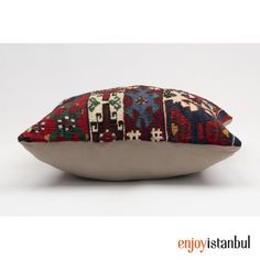 a decorative pillow with multicolored designs on the front and back, sitting on a white surface