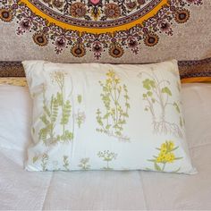 a white bed topped with a pillow and a decorative headboard over it's head