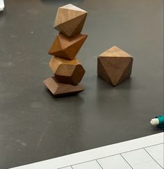 three wooden blocks sitting on top of a table next to a blue marker and pen