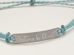 "This is an engraved waterproof bracelet, It is shown with an engraved brushed stainless steel bar and mint straps. You can choose your metal color and strap color. The bar will be engraved with \"Sisters in Christ\". You can choose back side engraving for personalization during checkout. Please let us know if you have any questions! The back can also be engraved. CHARACTER LIMIT- 14 characters per side Each item is made-to-order, which gives our pieces a unique meaning that is specific and spec Adjustable Engraved Name Bracelet For Friendship, Adjustable Silver Name Bracelet With Engraved Text, Adjustable Name Bracelet With Engraved Text As Gift, Adjustable Stainless Steel Name Bracelet With Engraving Option, Adjustable Stainless Steel Bracelets With Engraved Text, Adjustable Stainless Steel Bracelet With Engraved Text, Inspirational Engraved Adjustable Name Bracelet, Inspirational Engraved Name Bracelet, Adjustable, Adjustable Stainless Steel Bracelet With Laser Engraving