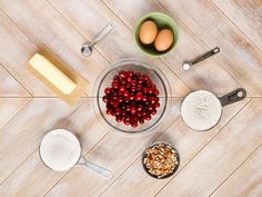 ingredients to make cranberry pie laid out on a wooden table with measuring spoons