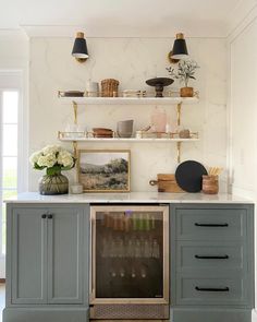 a kitchen with marble counter tops and gray cupboards, open shelving above the stove