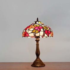 a lamp that is on top of a wooden table next to a gray wall and floor