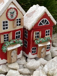 two red and white houses sitting on top of snow covered rocks next to a pine tree