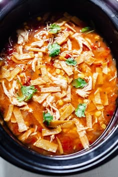 a crock pot filled with chicken tortilla soup and garnished with cilantro