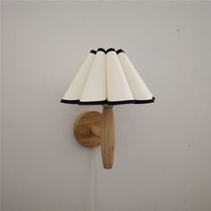 a lamp that is on the wall next to a wooden light fixture with a black and white shade