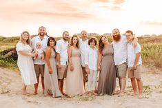 a group of people standing next to each other on top of a sandy beach at sunset