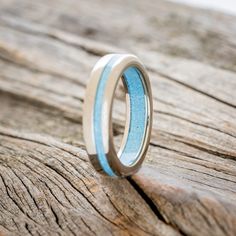 two wedding bands with blue and white enamel inlays on a piece of wood