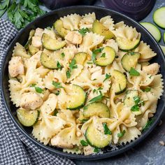 a bowl filled with pasta and cucumbers on top of a table