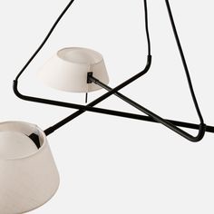 two lamps hanging from the ceiling, one with a white shade on it and one with a black cord