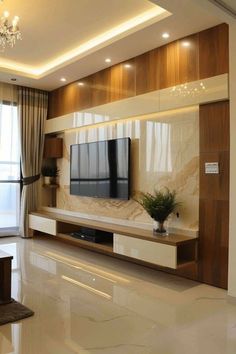 a living room with a large tv on top of a wooden entertainment center next to a window