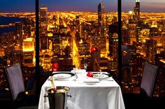 a table set for two with a view of the city at night