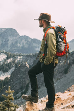 a man with a backpack standing on top of a mountain