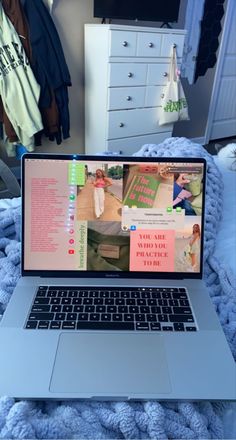 an open laptop computer sitting on top of a bed next to a blue comforter