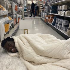 a young man is wrapped up in a blanket while shopping for blankets at the store