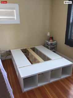 a bed room with a wooden floor and white furniture on it's side, next to a window