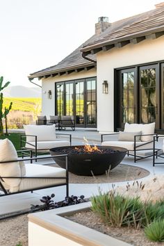 a fire pit sitting in the middle of a patio next to a white couch and chairs