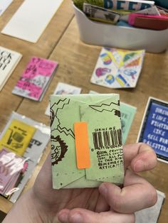 a person holding up a small piece of paper with an orange sticker on it