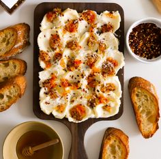 an assortment of breads and other foods on a cutting board next to a cup of tea