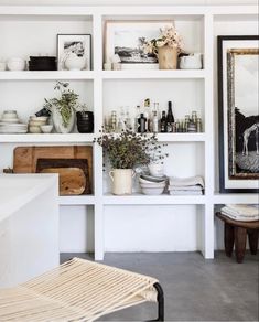 the shelves are filled with vases, pictures and other items in white painted walls