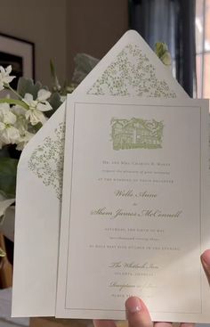 a person holding up a wedding card in their hand