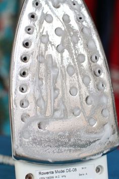 an iron that is sitting on top of a blue cloth covered table with white buttons