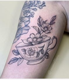 a black and white photo of a teacup with flowers on it's arm