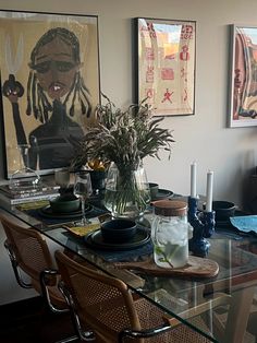 a glass table with chairs and pictures on the wall