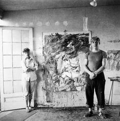 two men standing next to each other in front of a painting