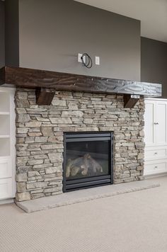 a stone fireplace in a living room with built - in shelving